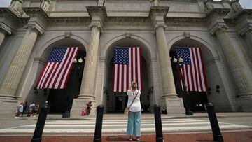 A woman takes a photo of flags flying in front Union Station ahead of the Fourth of July holiday,  in Washington, U.S,  June 27, 2023.  REUTERS/Kevin Lamarque