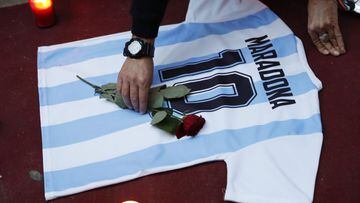 Soccer Football - People mourn the death of Argentine soccer legend Diego Maradona, Naples, Italy - November 26, 2020 A person places a rose on a Maradona Argentina shirt as people gather to mourn the death of Argentine soccer legend Diego Maradona in Nap