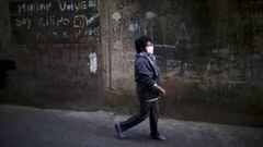 A woman, wearing a protective face mask to help curb the spread of the new coronavirus, walks past in the Villa 31 slum during a government-ordered shutdown, in Buenos Aires, Argentina, Thursday, April 30, 2020. According to official data, the number of confirmed cases of COVID-19 in the city&#039;s slum have increased in the past week, putting authorities on high alert. (AP Photo/Natacha Pisarenko)