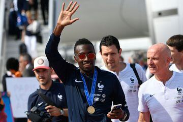 France's midfielder Blaise Matuidi (C), flanked by France's assistant coach Guy Stephan (R) waves to fans after disembarking from the plane with teammates upon their arrival at the Roissy-Charles de Gaulle airport on the outskirts of Paris, on July 16, 20