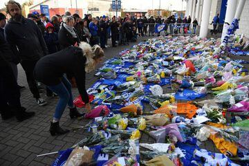 A woman (L) adds flowers to a growing pile of tributes outside Leicester City Football Club's King Power Stadium in Leicester