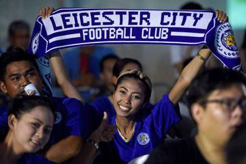 A Leicester fan in Bangkok holds a flag aloft