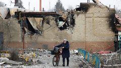 A woman walks with a bicycle next to a building damaged during Ukraine-Russia conflict in the separatist-controlled town of Volnovakha in the Donetsk region, Ukraine.