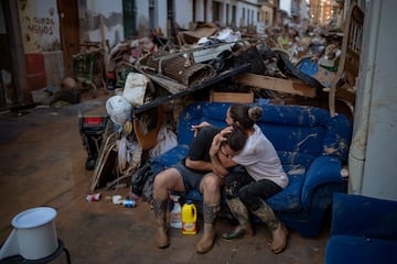 Vecinos de Paiporta se consuelan tras rescatar algunas de sus pertenencias de su casa.