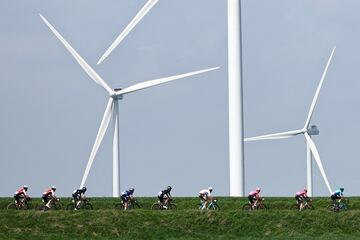 El grupo de ciclistas pasa junto a las turbinas eólicas.