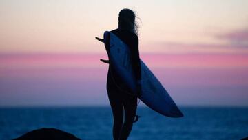 Stephanie Gilmore con su tabla de surf al atardecer en un clip para Nikon con la fotograf&iacute;a muy cuidada.