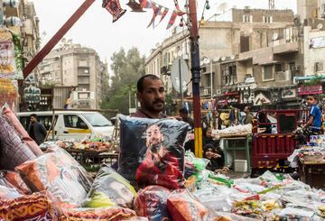 Un vendedor egipcio posa con una almohada de su mercancía en la que se puede ver al delantero egipcio del Liverpool Mohamed Salah en una calle de la capital, El Cairo.