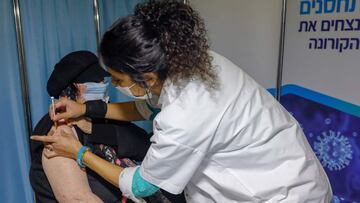 (FILES) In this file photo taken on January 14, 2021, an Israeli healthcare worker administers a COVID-19 vaccine to a woman at the Kupat Holim Clalit clinic in Jerusalem. - The Israel Prison Service said on January 17 it began vaccinating all incarcerated people against Covid-19, including Palestinians, following calls from rights groups, Palestinian officials and Israel's attorney general. (Photo by AHMAD GHARABLI / AFP)