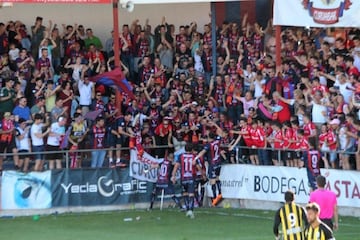 Quién le diría al Yeclano que tan solo un año después de ascender a Segunda División B iba a tener la posibilidad de jugar con los mejores. Para ello tendrá que superar un Playoff sin el apoyo de su público, fiel a su cita semanal en el Municipal La Constitución. El estadio puede albergar hasta 5.000 espectadores, pero quizás todavía no está preparado como para acoger un partido en LaLiga SmartBank. La temporada que viene, en caso de ascenso, quizás debería reconsiderar una mudanza temporal o una reforma paulatina para adaptarse a las condiciones que marca el profesionalismo. Entre tanto, Yecla entera se pegará al televisor para apoyar a los suyos y, en cuanto la pandemia lo permita, les homenajeará en el estadio por todo el esfuerzo realizado.
Pese a ser un recién ascendido y a pesar de que el estadio no es de los más monumentales de la categoría, el Yeclano se las ha apañado para ser el mejor local de todo el Grupo IV y, por tanto, uno de los mejores de Segunda División B. En él se han vivido ya tardes inolvidables y se han cerrado la mayoría de encuentros con un triunfo. Concretamente, diez de trece disputados. 33 puntos y un no tan buen balance como visitante, permiten al equipo de Sandroni lanzarse a una aventura inolvidable.