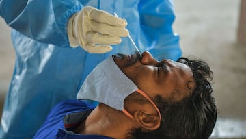 A health worker collects a sample from a passenger for a Reverse Transcription Polymerase Chain Reaction (RT-PCR) test at the Yesvantpur railway station in Bangalore on April 5, 2021. (Photo by Manjunath Kiran / AFP)