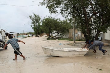 La gente mueve un bote después de que el huracán Milton trajera fuertes lluvias a la península de Yucatán en México en su camino a Florida.