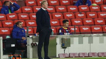 Barcelona's head coach Ronald Koeman watches his players from the side lines with Barcelona's Antoine Griezmann, left and Barcelona's Philippe Coutinho, right, behind in the substitutes area during the Spanish La Liga soccer match between B