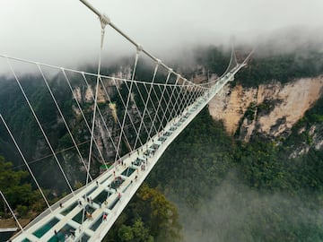 Este majestuoso puente está situado en Zhangjiajie, una ciudad de la provincia Hunan, en el noroeste de China. Se extiende a lo largo del cañón entre dos acantilados montañosos en el parque forestal nacional de Zhangjiajie. Su mayor atracción es que tiene un piso de vidrio transparente. Es el puente con piso de vidrio más largo y alto del mundo. Tiene 430 metros de longitud total y 6 metros de anchura, y está suspendido a 260 metros sobre el suelo.