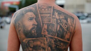 Un aficionado del Barcelona muestra en su espalda sus tatuajes de Lionel Messi, Ronaldinho e Iniesta, todos leyendas del club azulgrana, en los aledaños del Camp Nou antes de la rueda de prensa de Joan Laporta. El
anunciado adiós de la estrella argentina ha consternado a los seguidores culés.