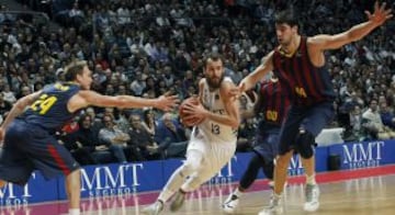 El base del Real Madrid Sergio Rodríguez (c) entra a canasta ante los jugadores del F.C. Barcelona, el croata Ante Tomic (d) y el escolta Brad Oleson (i), durante el partido correspondiente a la decimotercera jornada de Liga ACB que disputan en el Palacio de los Deportes de Madrid.