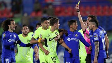 GETAFE, SPAIN - MARCH 13: Marcos Llorente of Atletico Madrid is held back by Luis Suarez of Atletico Madrid as he is shown a yellow card by referee Jose Maria Sanchez Martinez during the La Liga Santander match between Getafe CF and Atletico de Madrid at