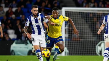 SAN SEBASTIÁN, 15/12/2024.- El centrocampista de la Real Sociedad Brais Méndez (i) en acción ante el delantero de la UD Las Palmas Dario Essugo (d) durante el partido de Liga disputado este domingo en el estadio Reale Arena. EFE/Javier Etxezarreta