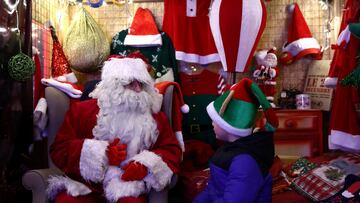 A man dressed as Santa Claus talks with a child at a Christmas village adorned with thousands of lights, in Beauvechain, Belgium, December 16, 2023. REUTERS/Yves Herman