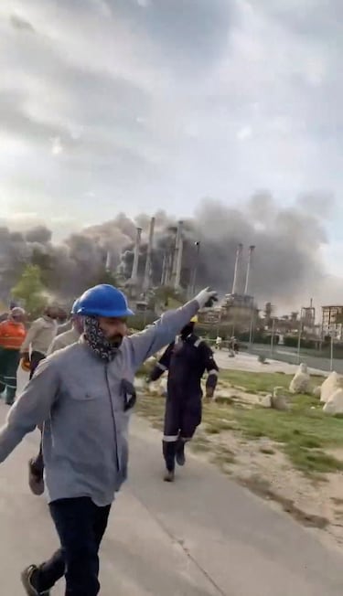 Trabajadores evacúan el área alrededor de la refinería mientras el humo se eleva tras un presunto ataque con drones iraníes, en Ras Tanura, Arabia Saudita.