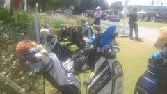 Bolsas de palos de golf en el 'bag drop' de las jugadoras, junto a los buggies y personal de seguridad en el Aramco Team Series de Sotogrande.