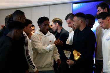 El delantero francés del Real Madrid Kylian Mbappe es saludado por sus compañeros de equipo tras recibir este viernes la Bota de Oro en un acto celebrado en el palco del Santiago Bernabéu.