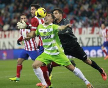 Los jugadores del Getafe CF, el portero Miguel Moyá (d) y Roberto Lago (c), luchan el balón con Raúl García (i), del Atlético de Madrid, durante el partido, de Liga en Primera División.