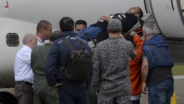 Miembros de la fuerza aerea brasileña suben al jugador Alan Rushell al avión.