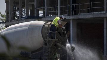 Un operario limpia con una pistola de agua a presión un camión hormigonera.