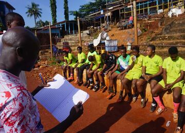 Los miembros del equipo de ftbol del Centro de Servicios Correccionales de mujeres escuchan a sus entrenadores durante el entrenamiento en el campo de ftbol comunitario Parade en Freetown.