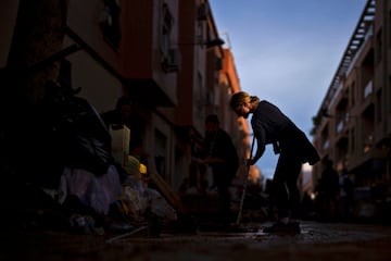 Una mujer limpia el barro de una de las calles afectada por las inundaciones en Sedavi, España.