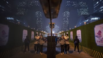BEIJING, CHINA - NOVEMBER 18: A man adjusts the mask on a woman's face as they walk in the street during rush hour on November 18, 2021 in the Central Business District on a polluted day in Beijing, China. While China has mostly contained the spread of COVID-19, and even though cases remain relatively low, the recent spread of the Delta variant has caused the government to reinforce stricter health measures. Mask mandates, mass testing, immunization boosters, quarantines, and some travel restrictions have become the norm as China continues to maintain its zero-COVID policy. (Photo by Kevin Frayer/Getty Images)