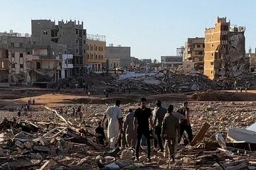 Varias personas caminan entre los escombros en Derna. La fuerza del agua arrastró edificios enteros hasta el mar con sus habitantes dentro.  
