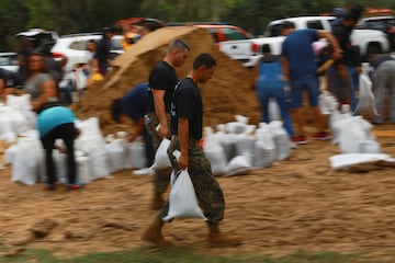 Los marines estadounidenses ayudan a los residentes a cargar sacos de arena antes de la llegada del huracán Milton.