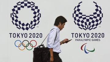 Un peat&oacute;n pasa junto a los logos de Tokio 2020, en la capital japonesa. 