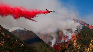 An aircraft drops flame retardant as firefighters battle the Woolsey Fire as it continues to burn in Malibu, California.November 11, 2018. 