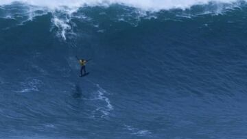 Kai Lenny realizando un salto con su tabla de surf en una ola gigante en Nazaré, justo después de realizar una maniobra nunca vista en una ola tan grande.
