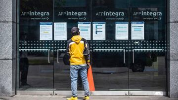 A man looks for information at the front door of Integra AFP (Pension Fund Administration) office in Lima on May 18, 2020. - More than six million Peruvians can request as of Monday the withdrawal of up to 3,700 US dollars from their pension funds to alleviate the economic crisis caused during the  two months lockdown imposed by the government to fight the spread of the novel Covid-19 coronavirus. (Photo by Ernesto BENAVIDES / AFP)