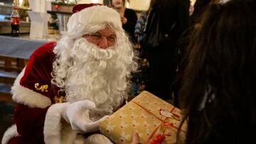 24 December 2022, Berlin: A "Santa Claus" distributes donated gifts to children at the Hofbräuhaus in Berlin. The Christian children's and youth charity "Die Arche" invited financially disadvantaged families in particular to eat poultry, red cabbage and dumplings together on Christmas Eve. Photo: Christophe Gateau/dpa (Photo by Christophe Gateau/picture alliance via Getty Images)