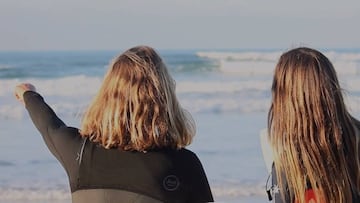 Nadia Erostarbe y June Erostarbe, de espaldas y con neopreno, se&ntilde;alando las olas para surfear en la playa de Zarautz (Gipuzkoa). Ambas participan en Glassy, el documental de surf femenino en el Pa&iacute;s Vasco. 
