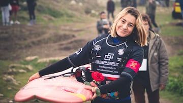 Laura Coviella con una rosa y una tabla de surf yendo al agua en el campeonato de surf de olas grandes La Vaca Gigante, el 21 de febrero del 2024 en Santander, Cantabria.