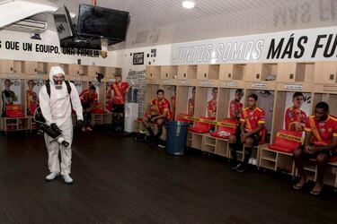 Los futbolistas del Sport Herediano de Costa Rica Christian Reyes, Mauricio Núñez, Aaron Salazar, Orlando Galo y Keyner Brown esperan en el vestuario mientras un operario del club desinfecta las instalaciones antes de un entrenamiento. El fútbol profesional en Costa Rica volvió a los entrenamientos.