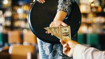 The hand of the waitress takes the tip. The waiter girl receives a tip from the client at the hotel bar. A bartender woman is happy to receive a tip at work. The concept of service.