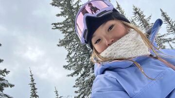 La snowboarder Chloe Kim con máscara de nieve y unos árboles detrás.
