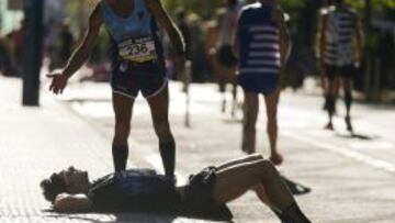 Un atleta descansa sobre la acera tras atravesar la línea de meta, durante la 51 edición de la carrera popular Behobia-San Sebastián, en la que participan 34.000 personas.