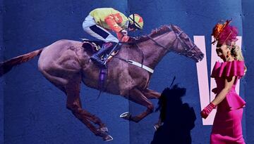 El hipódromo de Aintree, en Liverpool, celebró el Día de las Damas, durante la segunda jornada del Grand National Festival, la carrera de caballos de obstáculos más importante de las que tienen lugar en Reino Unido. En la imagen, una mujer pasa junto a un cartel ecuestre con un elegante vestido y un pomposo sombrero.