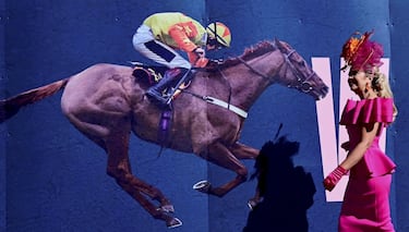 El hipódromo de Aintree, en Liverpool, celebró el Día de las Damas, durante la segunda jornada del Grand National Festival, la carrera de caballos de obstáculos más importante de las que tienen lugar en Reino Unido. En la imagen, una mujer pasa junto a un cartel ecuestre con un elegante vestido y un pomposo sombrero.