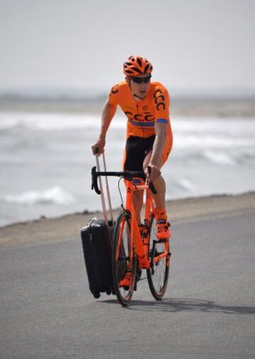 El ciclista polaco Adrian Kurek llega a la playa de Sawadi con una maleta, para iniciar la primera etapa del Tour de Omán.