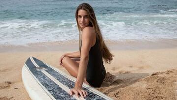 La surfista Emi Erickson posando con su tabla de surf en una playa de Hawái.