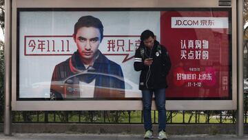 Un hombre usa un tel&eacute;fono inteligente mientras espera en una parada de un autob&uacute;s en la que se publicita una tienda online durante el &quot;D&iacute;a del Soltero&quot;, en Pek&iacute;n (China), en una fotograf&iacute;a de archivo. EFE/Rolex Dela Pena