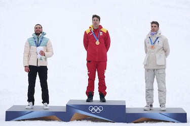 El medallista de oro Oriol Cardona Coll (España), el medallista de plata Nikita Filippov (Individual Neutral) y el medallista de bronce Thibault Anselmet (Francia) participan en el himno nacional durante la ceremonia de entrega de medallas de la prueba de velocidad masculina de esquí de montaña.